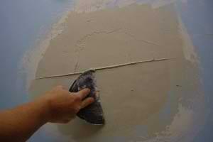 photo smoothing joint compound over plaster damage